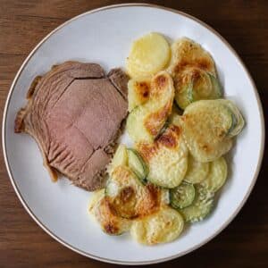 Création d'une photo (Format d'image jpg png; Taille de l'image = 500 Ko; taille 560 800). d'un plat vu du haut dressé dans une assiette du plat gratin de pomme de terre et courgette, accompagné