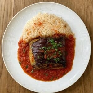 Création d'une photo (Format d'image jpg png; Taille de l'image = 500 Ko; taille 560 800). d'un plat vu du haut dressé dans une assiette du plat aubergine farcie à la viande hachée pliée en 4 (1)