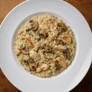 Création d'une photo (Format d'image jpg png; Taille de l'image = 500 Ko; taille 560 800). d'un plat vu du haut dressé dans une assiette du plat risotto aux champignon poulet de façon réaliste