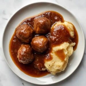 Création d'une photo pesant maximum 300ko format carrée 1 1 d'un plat vu du haut dressé dans une assiette du plat boulette sauce liégeoise, avec de la purée de pomme de terre façon réaliste