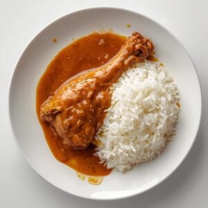 Création d'une photo pesant maximum 300ko format carrée 1 1 d'un plat vu du haut dressé dans une assiette du plat cuisse de poulet sauce cacahuète accompagné de riz de façon réaliste (2)