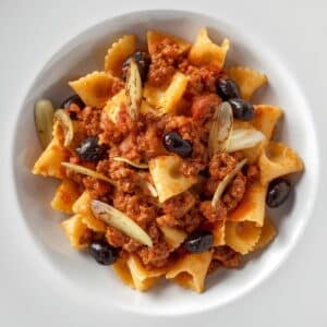 Création d'une photo pesant maximum 300ko format carrée 1 1 d'un plat vu du haut dressé dans une assiette du plat « farfale bolognaise au fenouil et olive» de façon réaliste