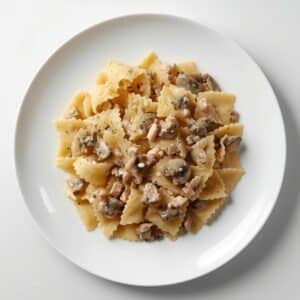 Création d'une photo pesant maximum 300ko format carrée 1 1 d'un plat vu du haut dressé dans une assiette du plat «farfalle crème de champignon avec des dés de poulet » de façon réaliste